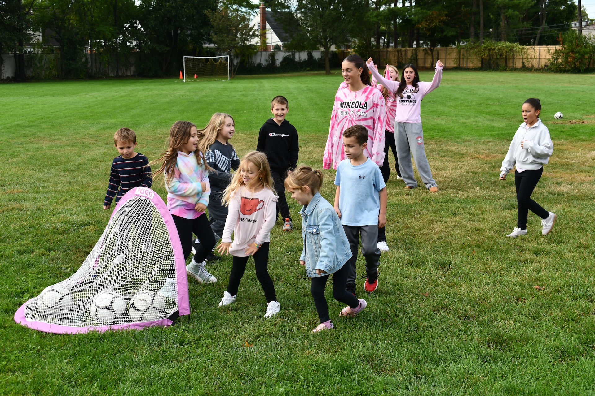 Younger student play soccer on a field with high school students